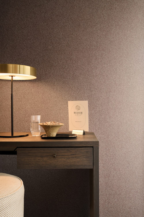 Versatile in design, Omexco's High Performance Essence wallpaper in warm textured browns enhances spa, bedroom, and workspace interiors with a refined, calming look.