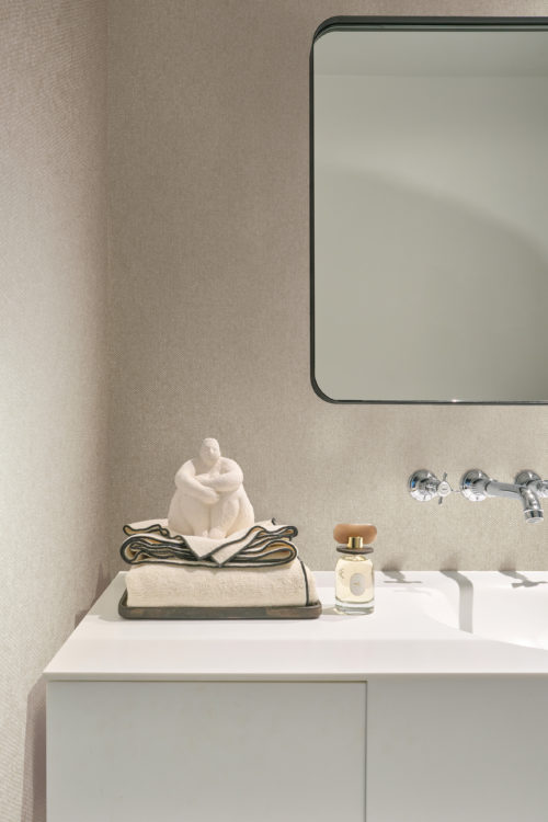 Omexco's High Performance Essence wallpaper in soft beige, paired with white accents and subtle lighting for a clean, elegant look.