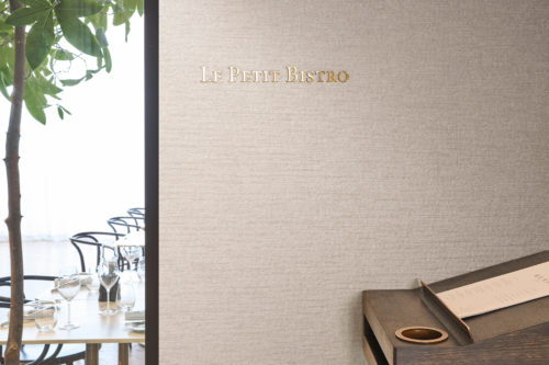 Omexco's High Performance Essence wallpaper in a light textured beige, bringing understated elegance to a bistro entrance with refined details.