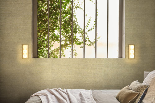 In the Virginia’s Garden collection, Omexco highlights the quiet elegance of textured wallpaper in a muted green tone, where subtle depth and organic weave bring a sense of nature indoors. Framed by soft light filtering through leafy vines at the window, the bedroom becomes a sanctuary of calm, its layered textiles and simple lines echoing the serenity of the outdoors. The design balances refinement and comfort, offering a timeless retreat that feels both modern and rooted in the natural world.
