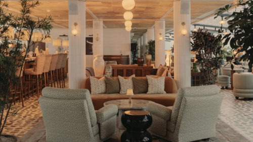 Warm, moody dining area at Soho House Manchester with round tables, striped banquettes and a mulberry-toned ceiling finished in natural textured panels.