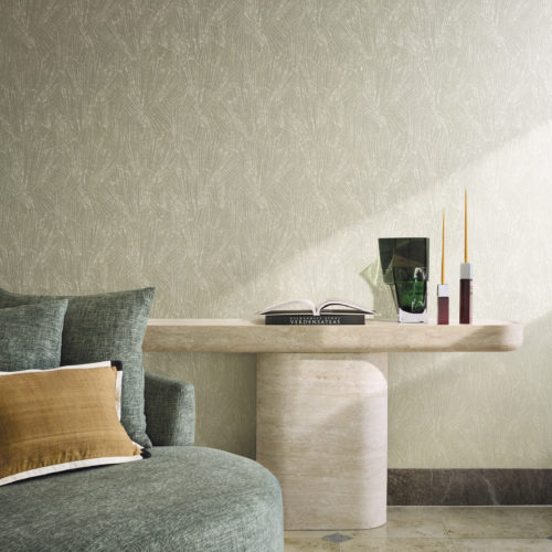 Raumgestaltung mit der Whisper Wandbekleidung von Omexco, die ein stilisiertes Motiv zeigt, inspiriert von feinen mineralischen Strukturen und Muscheln. Die hellgrüne strukturierte Wand dient als eleganter Hintergrund für einen grünen Sessel, einen Steinkonsolentisch und eine dunkelgrüne Glasvase.