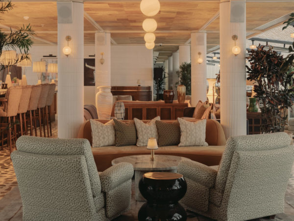 Warm, moody dining area at Soho House Manchester with round tables, striped banquettes and a mulberry-toned ceiling finished in natural textured panels.